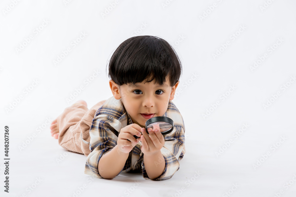 Child holding magnifying glass on white background. Boy with a magnifying glass in studio. Child holding magnifying glass on white background. Boy with a magnifying glass in studio.