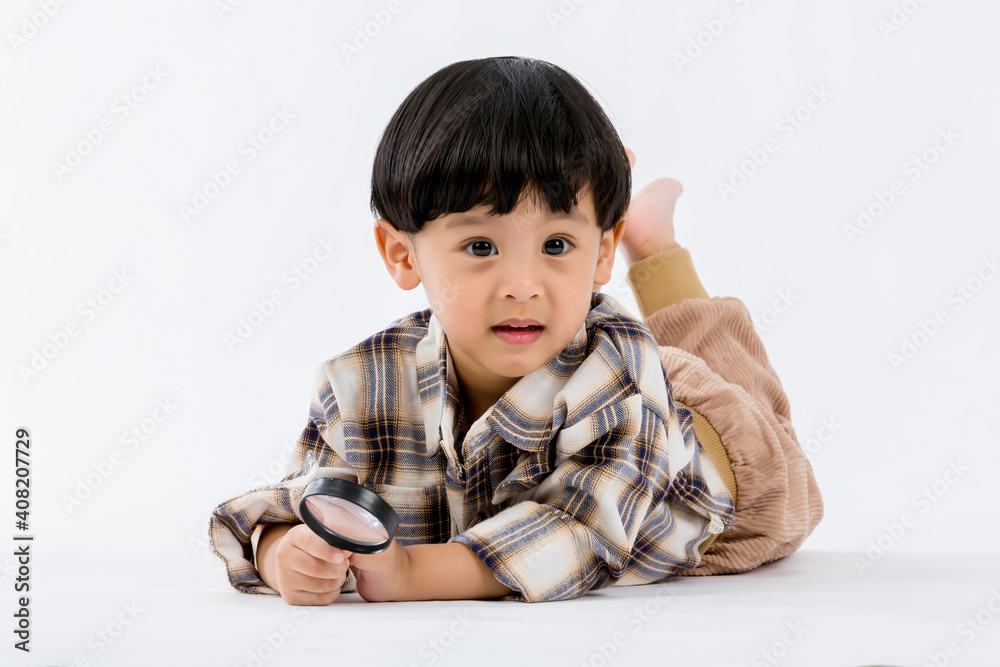 Child holding magnifying glass on white background. Boy with a magnifying glass in studio. Child holding magnifying glass on white background. Boy with a magnifying glass in studio.