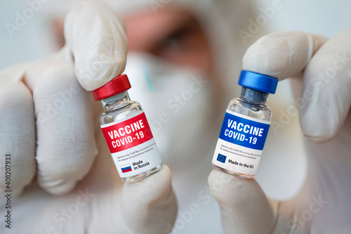 Two bottles of covid 19 coronavirus vaccine and a syringe on white table. The medical conception of combating the covid-19 pandemic.