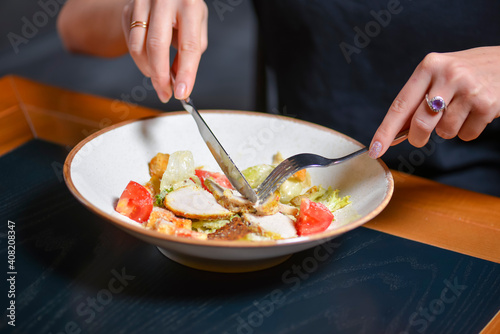 Young woman eats caesar salad of traditional recipe in restaurant or diner. Eating out concept.