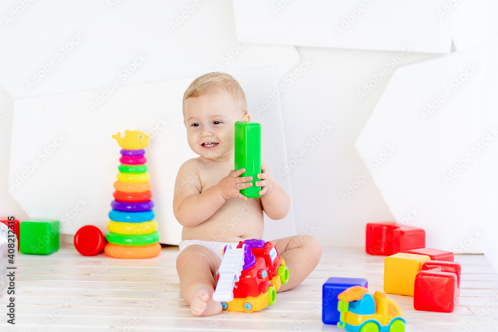 a small child a boy six months old plays with bright toys in a bright white room in diapers a small child a boy six months old plays with bright toys in a bright white room in diapers