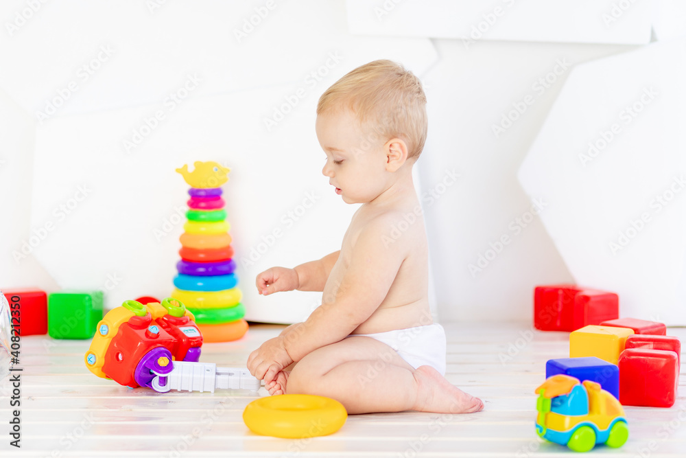 a small child a boy six months old plays with bright toys in a bright white room in diapers a small child a boy six months old plays with bright toys in a bright white room in diapers