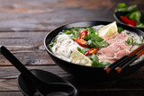 Vietnamese soup Pho Bo with beef and noodles on a wooden background, selective focus