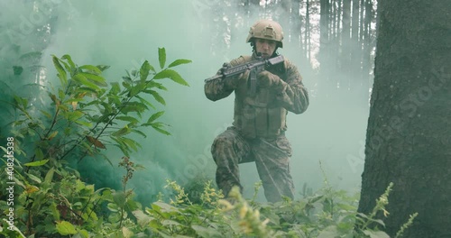 Soldiers running millitary action in dense forest with smoke in backgorund, army conducting action in forest