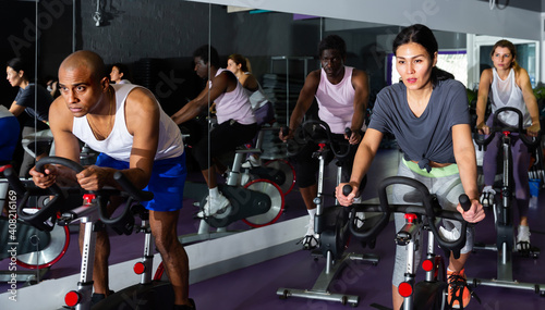 Adults working out of cycling in modern fitness club