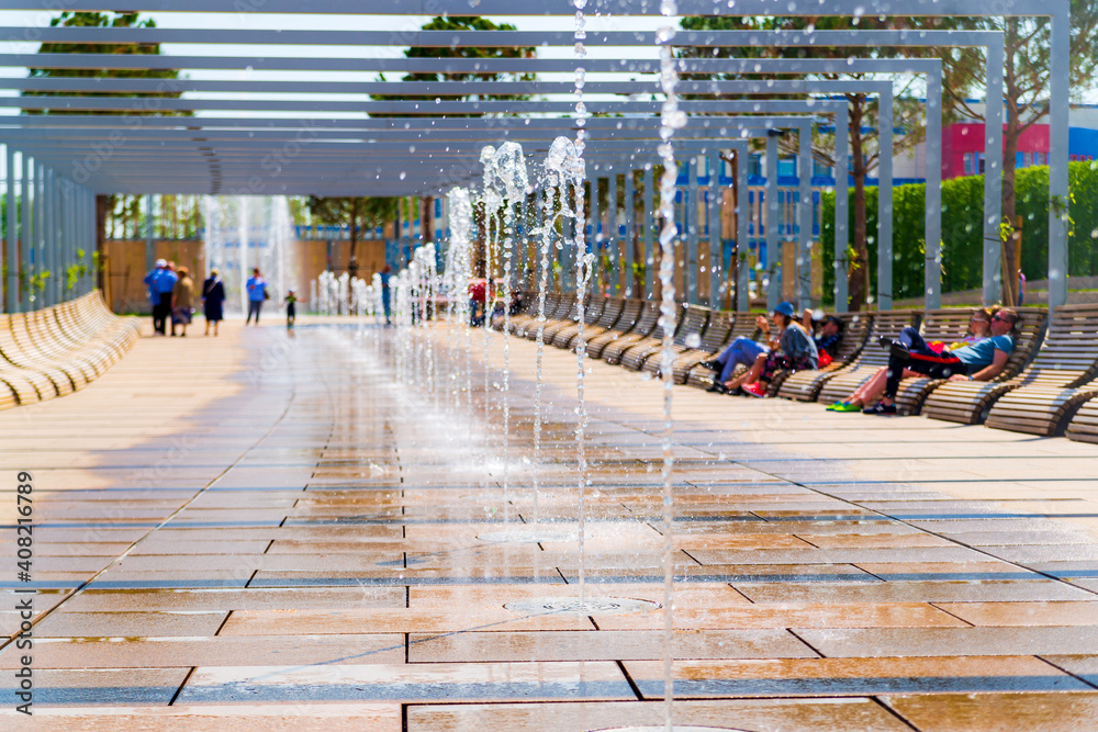 Obraz premium Row of fountains in a park at a high shutter speed freezing the motion of the water and suspended droplets with variety of shape, like a crystal or ice isolated with beautiful bokeh
