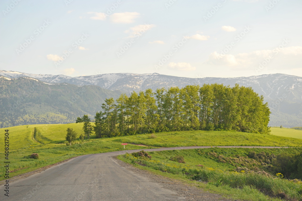 Ridder, Kazakhstan - 06.05.2013 : A road laid along a mountainous and hilly area with trees, shrubs and various types of grass.