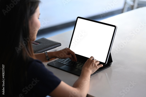 Fotografie Rear view of female freelancer working on tablet computer while sitting at comfortable workplace