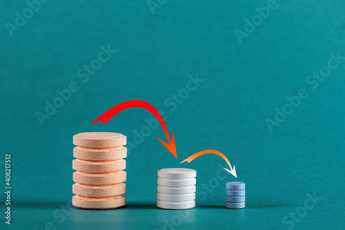 Stacks of pills on a blue background. Medical concept of reducing drug consumption as you recover