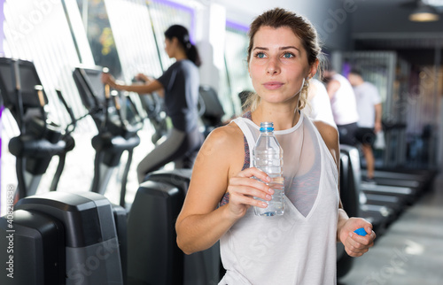 Positive woman with bottle of water in a sports club © JackF