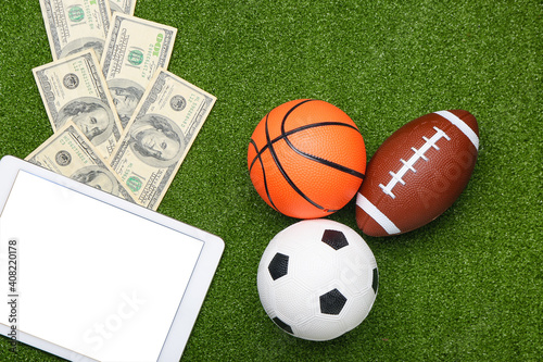 Money, balls and tablet computer on color background. Concept of sports bet