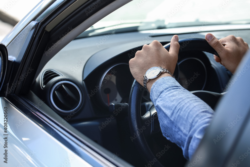 Handsome man with stylish wristwatch driving car