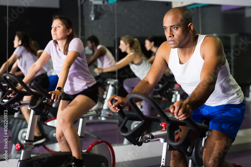Portrait of sporty man training on stationary bike in gym