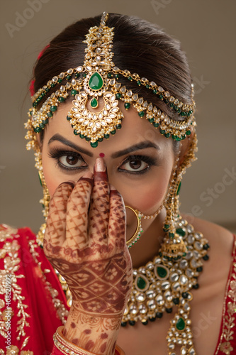 Beautiful Indian bride putting a bindi on the forehead	 photo