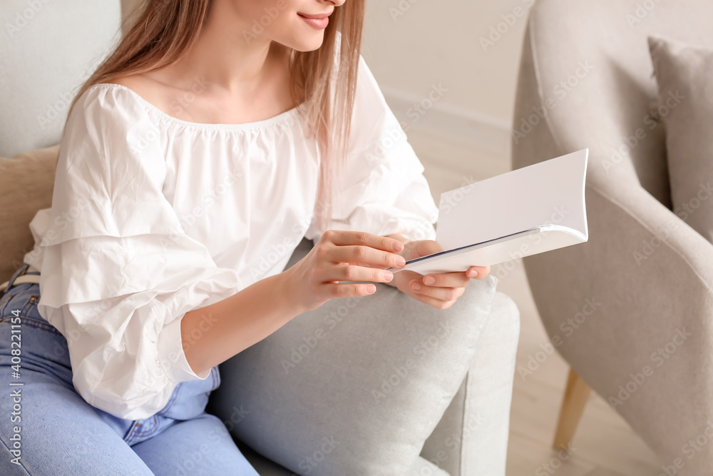 Beautiful woman reading blank magazine in living room Beautiful woman reading blank magazine in living room