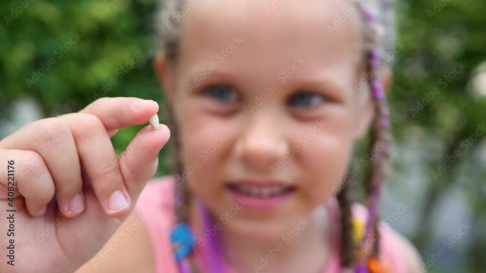 Little girl with wobbly first milk temporary tooth. Dental medicine or mouth healthcare concept Little girl with wobbly first milk temporary tooth. Dental medicine or mouth healthcare concept
