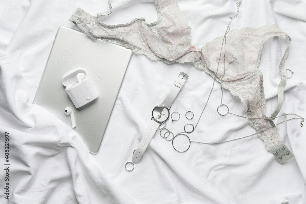 Stylish wristwatch, gadgets and jewelry on light fabric background