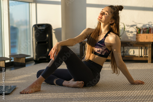 Young attractive woman practicing yoga and relaxing,sitting in front of laptop screen.Fitness and Yoga online training concept in the  coronavirus pandemic.Healthy lifestyle.Slow living concept.