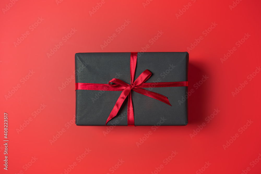 Black gift box with red bow on red background top view, Valentines day, Flat lay style with copy space. Black gift box with red bow on red background top view, Valentines day, Flat lay style with copy space.