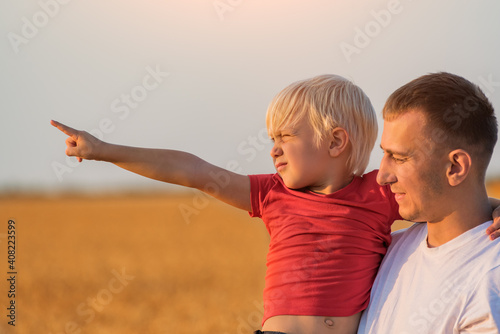 Child hugs dad and pointing into distance. Father and son walk together