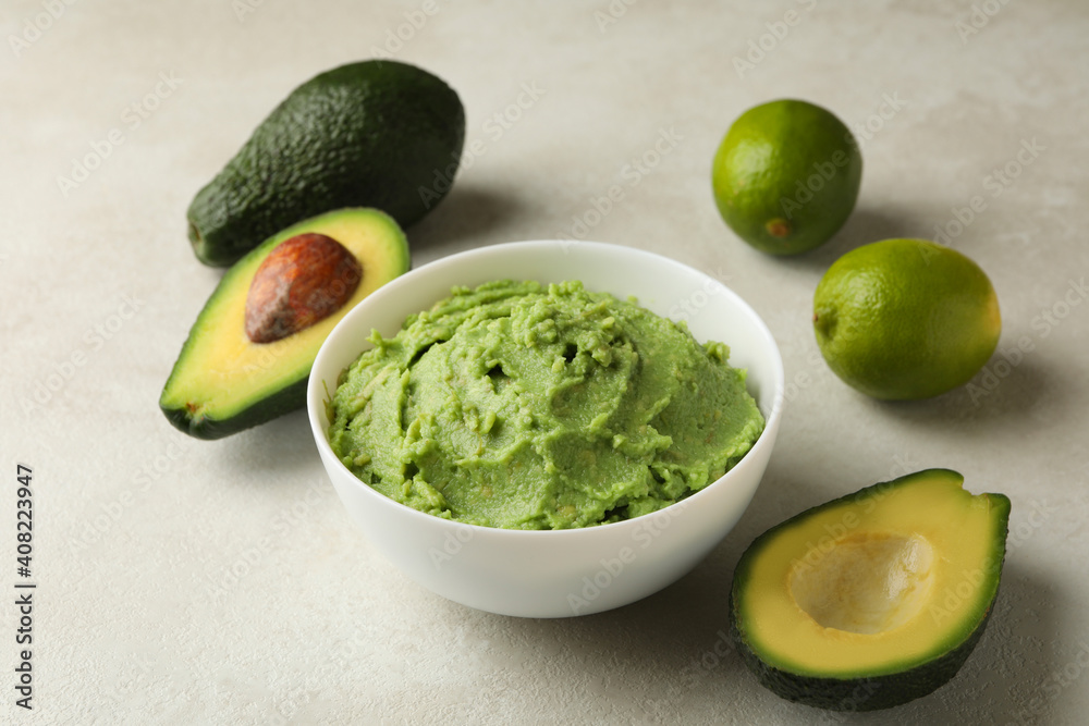 Bowl of guacamole, avocado and lime on white textured background, close up Bowl of guacamole, avocado and lime on white textured background, close up