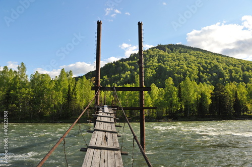 Ridder, Kazakhstan - 06.05.2013 : The bridge is made of old wood and metal rods and rebar. The Irtysh River. photo