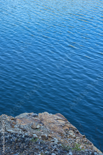 Stone rocks near water, on the background of lake, river, sea, ocean. Blue clear water. Artificial reservoirs
