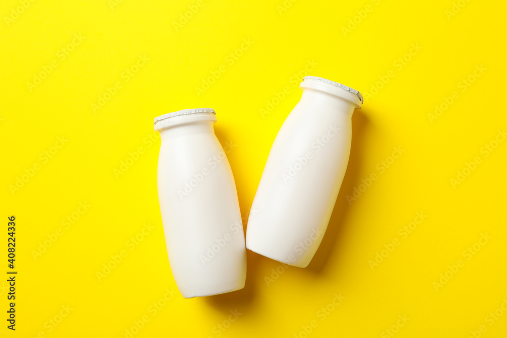 Blank bottles with yogurt on yellow background Blank bottles with yogurt on yellow background