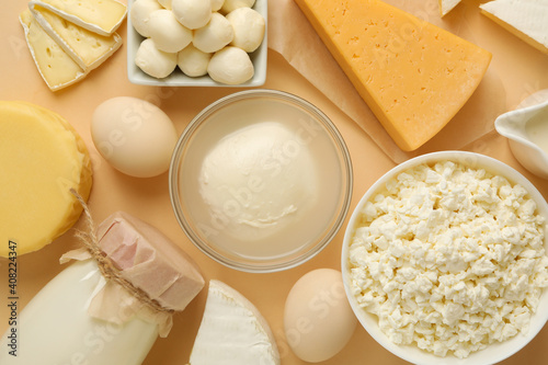 Different fresh dairy products on beige background, top view