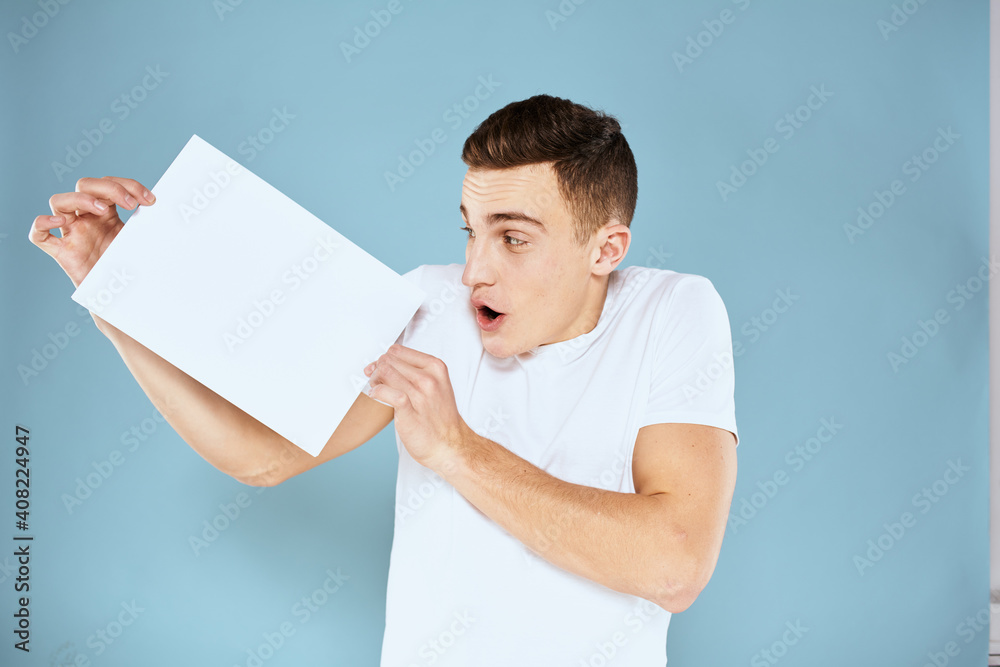 a man in a white t-shirt holds a sheet of paper copy space a man in a white t-shirt holds a sheet of paper copy space