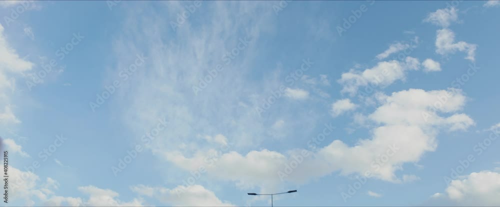 Blue sky with several white clouds. Camera tilted up to sky while driving in town. Car driver's point of view. Blue sky with several white clouds. Camera tilted up to sky while driving in town. Car driver's point of view.