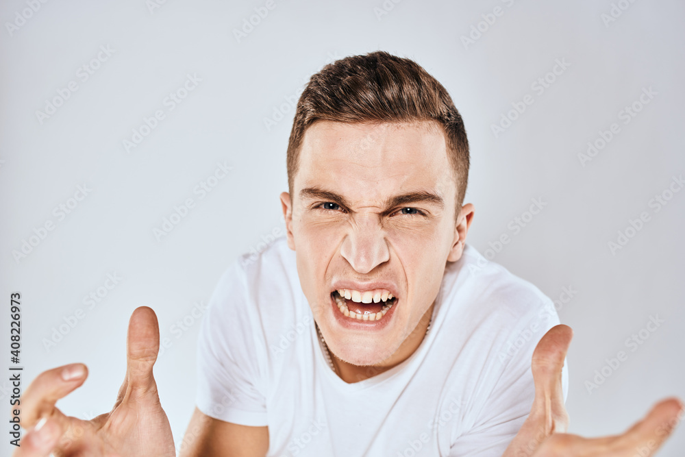 Man in white t-shirt displeased facial expression gesturing with hands studio lifestyle Man in white t-shirt displeased facial expression gesturing with hands studio lifestyle
