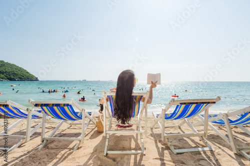 A girl enjoys reading book on the beach