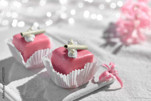 Valentine petit fours with marzipan icing. Fragrant pink hyacinth flower. Garland of lights on white textile. Happy Valentine's day Romantic evening at home. photo