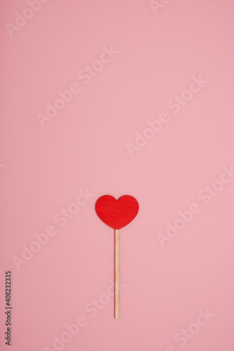 Red wooden love heart on a pink pastel background
