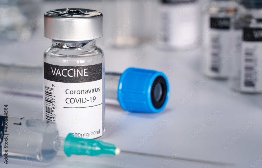 Covid-19 vaccine and syringe injection on a laboratory bench. to fight the coronavirus sars-cov-2 pandemic. Medicine infectious concept.