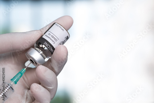 Doctor's hand holds a syringe and a vaccine covid19 bottle at the hospital. Health and medical concepts with soft focus background. counterfeit QR code or barcode