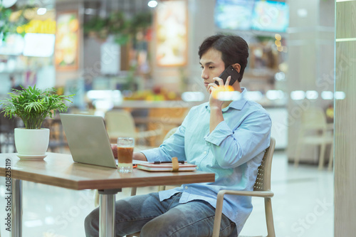 Asian man sitting working alone at a coffee shop