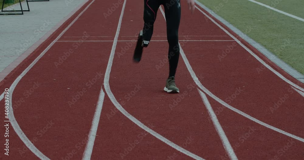 Crop view of disabled male person with prosthetic running blade at track on sports field. Amputee male sportsman jogging. Concept of motivational sports footage, paralympic. Crop view of disabled male person with prosthetic running blade at track on sports field. Amputee male sportsman jogging. Concept of motivational sports footage, paralympic.