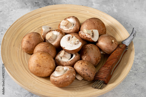 Mushrooms in a wooden plate on the light gray kitchen table. Champignons
