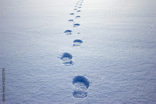 Human footprints in the snow under sunlight close-up view