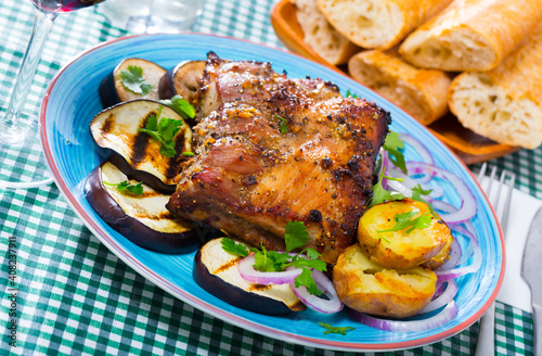 Baked pork rib served with potato and grilled eggplants on plate