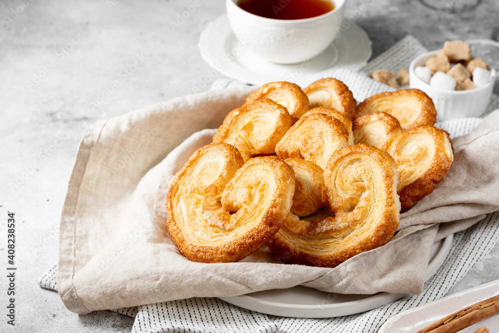 Puff. Flaky sugar Palmiers cookies in a ceramic plate on a light background. Sweet homemade cakes