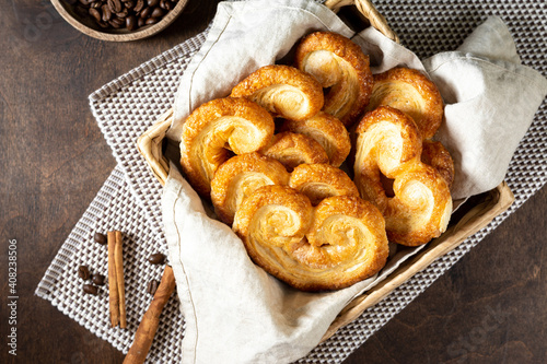 Puff. Flaky sugar Palmiers cookies in a basket on a light background. Sweet homemade cakes	