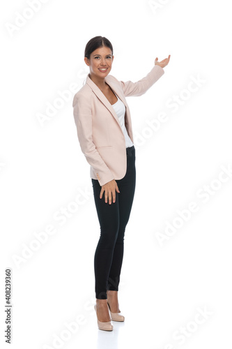 confident young female in pink jacket presenting to side and smiling