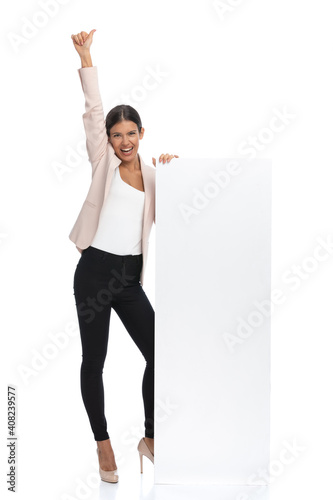 full body picture of happy woman standing next to empty board