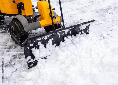 Schnee schieben mit einem Traktor auf dem Fußweg