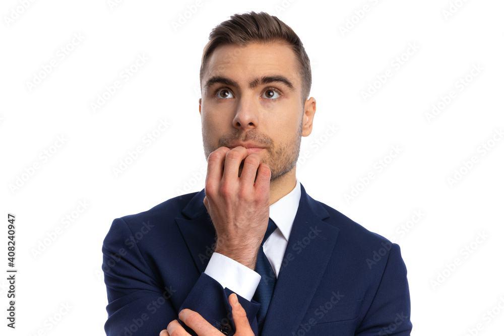 timid young man looking up and holding hand to chin timid young man looking up and holding hand to chin
