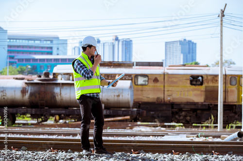 Portrait engineer under inspection and checking construction process railway and checking work on railroad station .Engineer wearing safety uniform and safety helmet in work.
