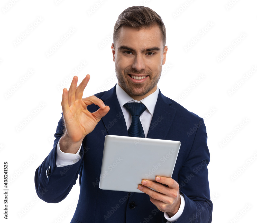 attractive unshaved guy in navy blue suit holding tab and smiling attractive unshaved guy in navy blue suit holding tab and smiling